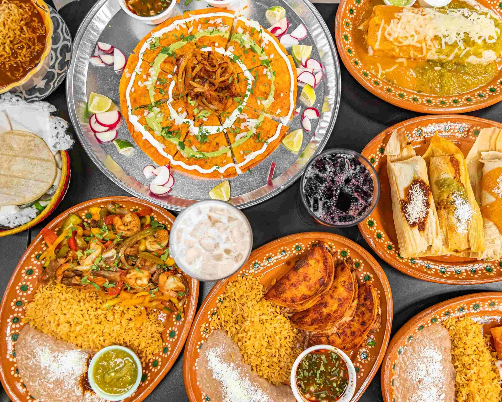 Don José food spread with birria tacos, tamales and drinks